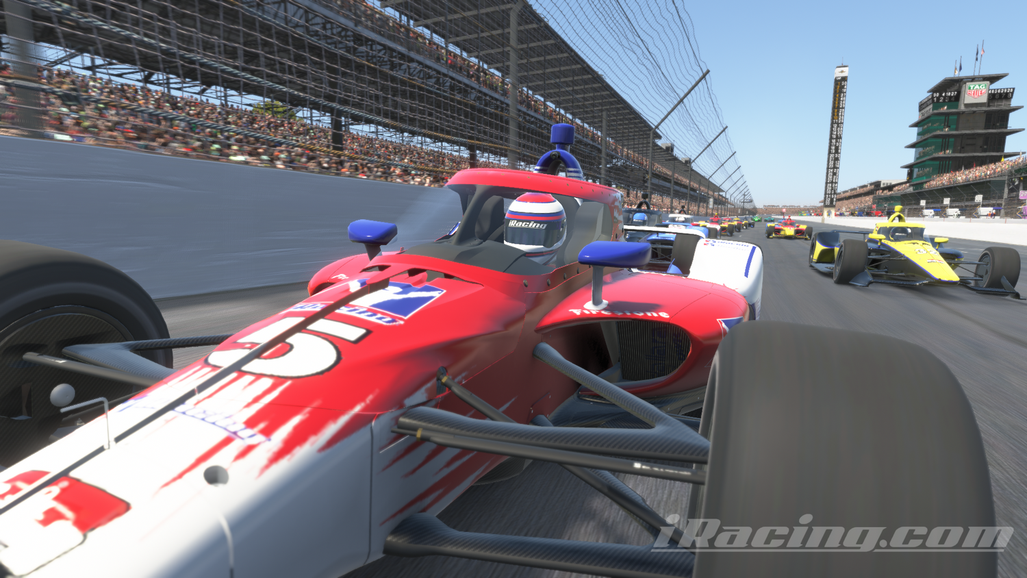 Close-up of a red and white IndyCar with the number 5 on the front, racing down the straightaway at the Indianapolis Motor Speedway. The driver, wearing a helmet with iRacing branding, is focused ahead. Multiple cars follow closely behind, including a yellow car. The grandstands are packed with spectators, and the iconic scoring pylon tower is visible in the background under a clear blue sky. iRacing screenshot.